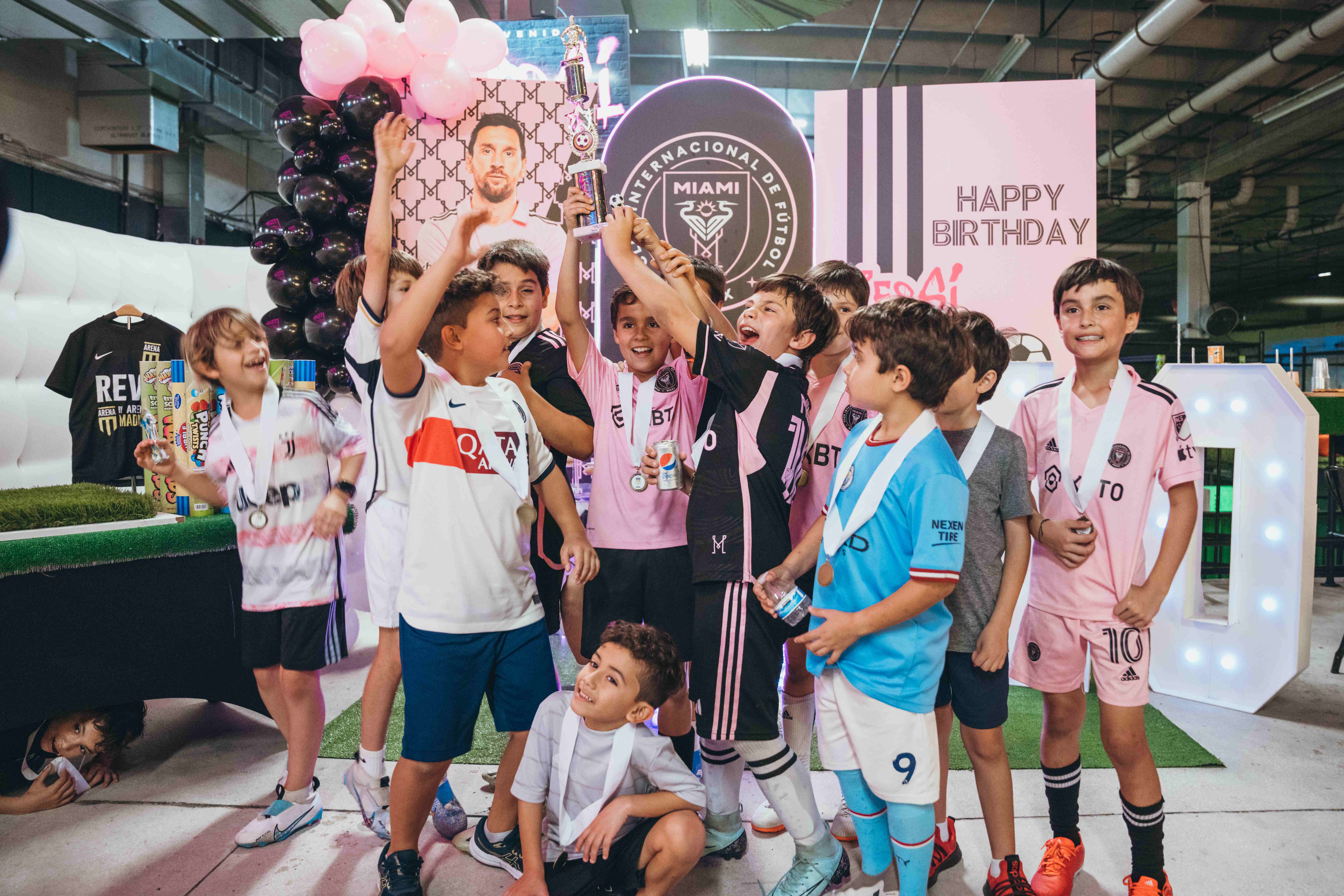 Children celebrating at a soccer-themed birthday party with trophy