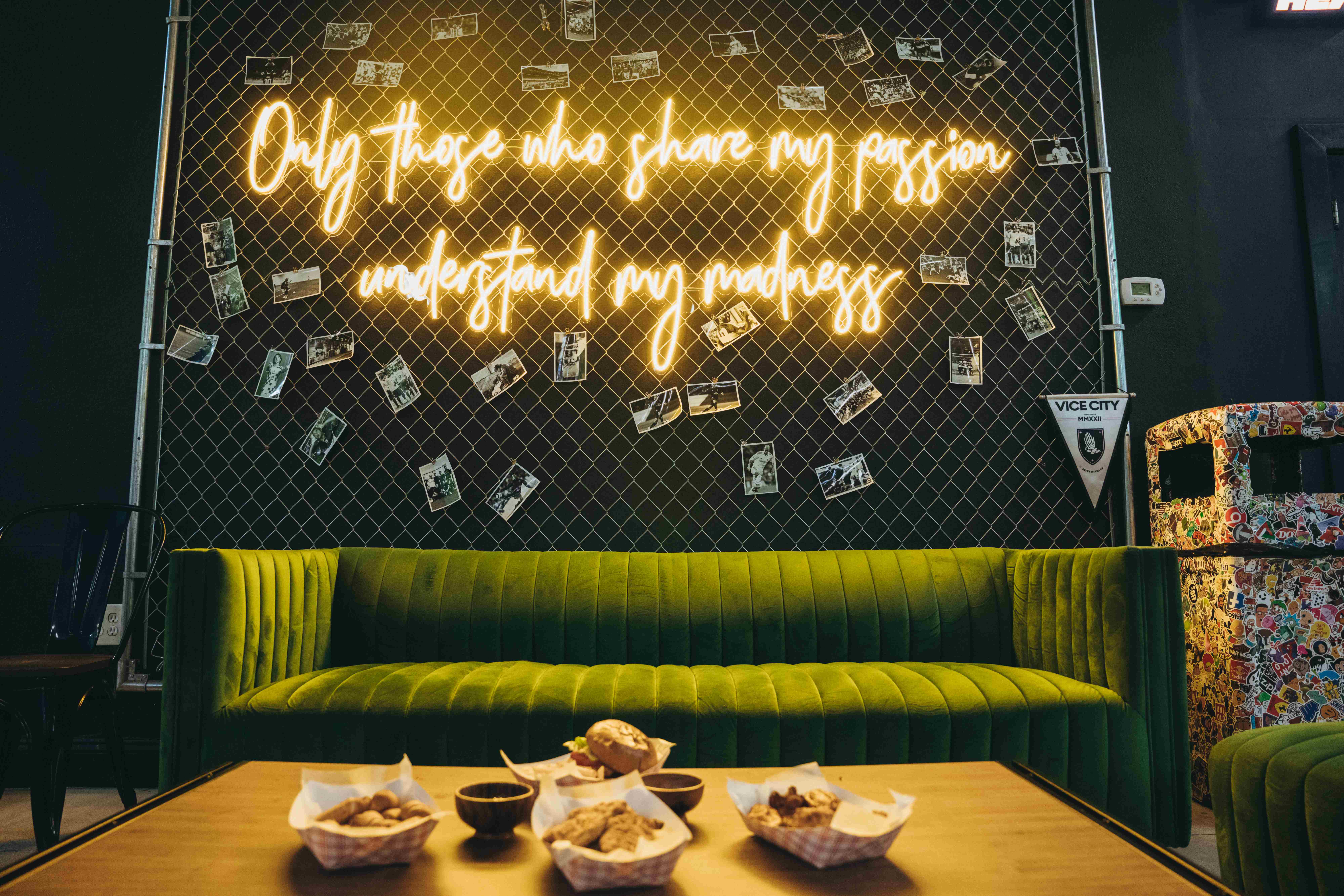 Stylish lounge area with neon sign and green velvet couch for corporate events